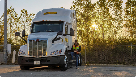 driver poses with truck nears in the back of a lot