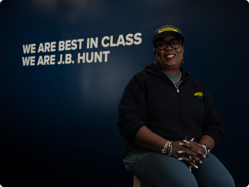 female driver in front of sign that says "We are best in class, We are J.B. Hunt"