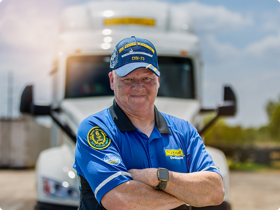 Veteran driver wearing Navy hat in front of truck