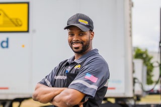 j.b. hunt driver ronnie smiiles in front of a truck trailer