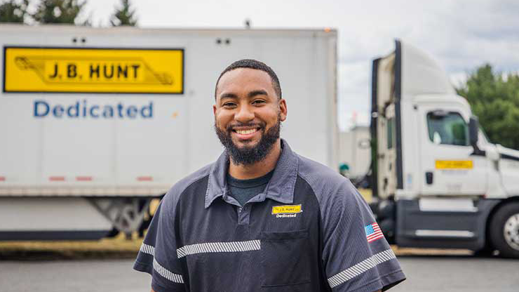 J.B. Hunt dedicated driver standing next to truck.