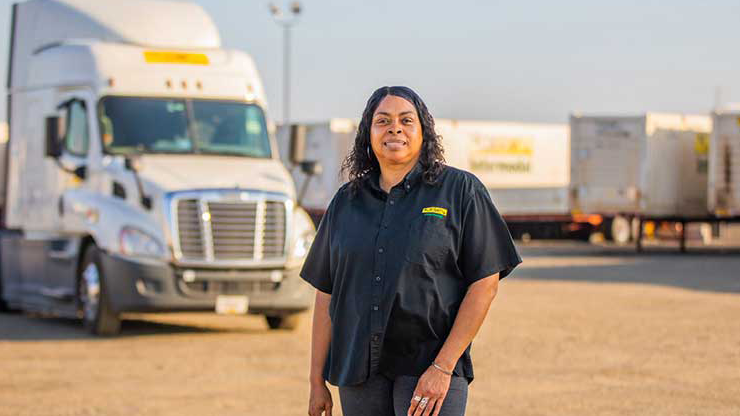 J.B. Hunt intermodal driver in front of a tractor trailer in a truck yard