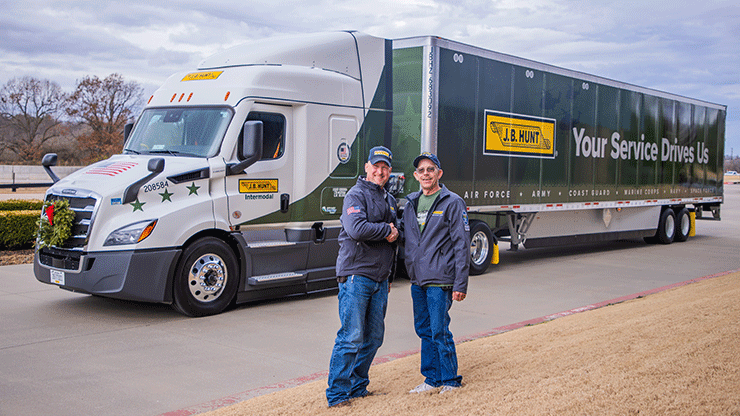 Two drivers shaking hands in front of a J.B. Hunt Wreaths Across America truck.